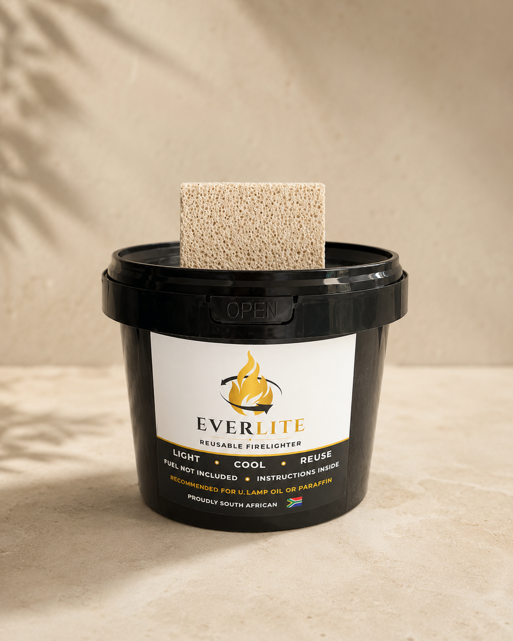 EverLite reusable firelighter black container with stone beside it